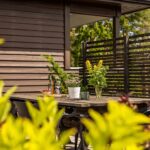 Moderner Holzzaun mit horizontalen Lamellen in naturbelassenem Ton vor Gartenkulisse