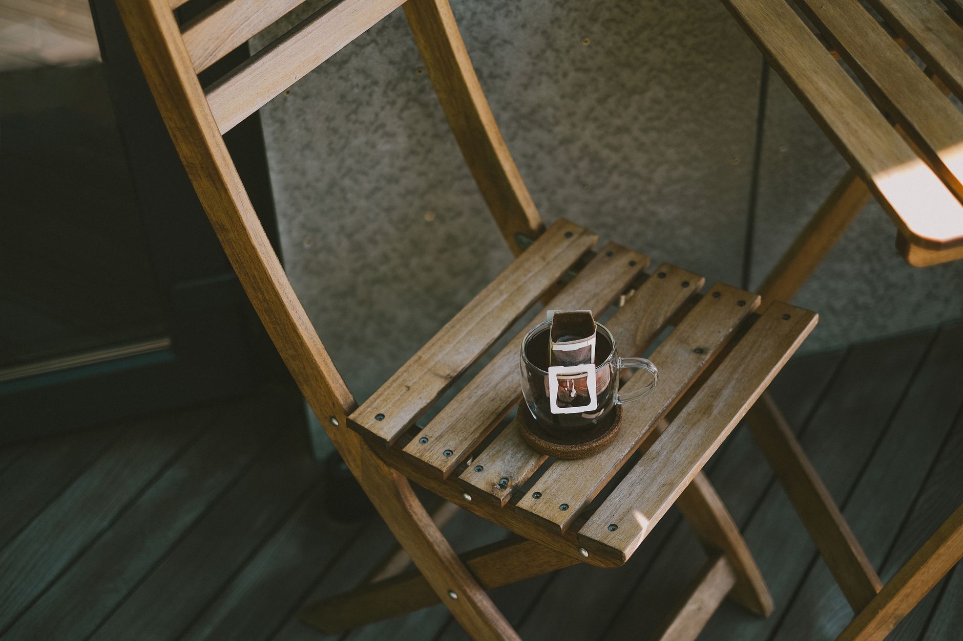Holzstuhl mit Filterkaffeemaschine auf einer Terrasse, der eine friedliche Morgenstimmung schafft.