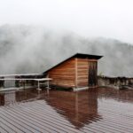 Ein ruhiger, nebliger Waldblick von einer regennassen Holzterrasse in Deutschlandsberg, Österreich.