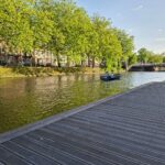 Ein wunderschöner Kanal mit üppig grünen Bäumen und einer Brücke im Frühling.