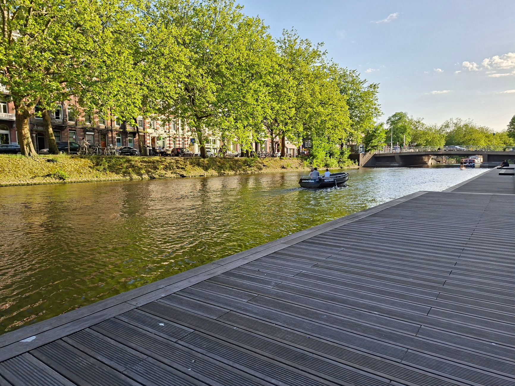 Ein wunderschöner Kanal mit üppig grünen Bäumen und einer Brücke im Frühling.